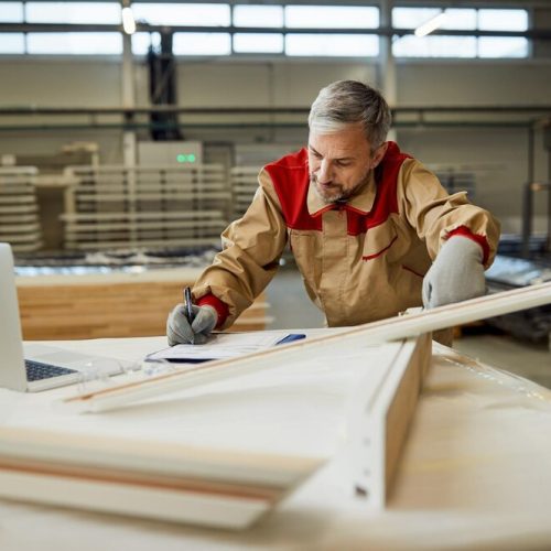 mid-adult-worker-taking-notes-while-checking-measurements-carpentry-workshop_637285-11695